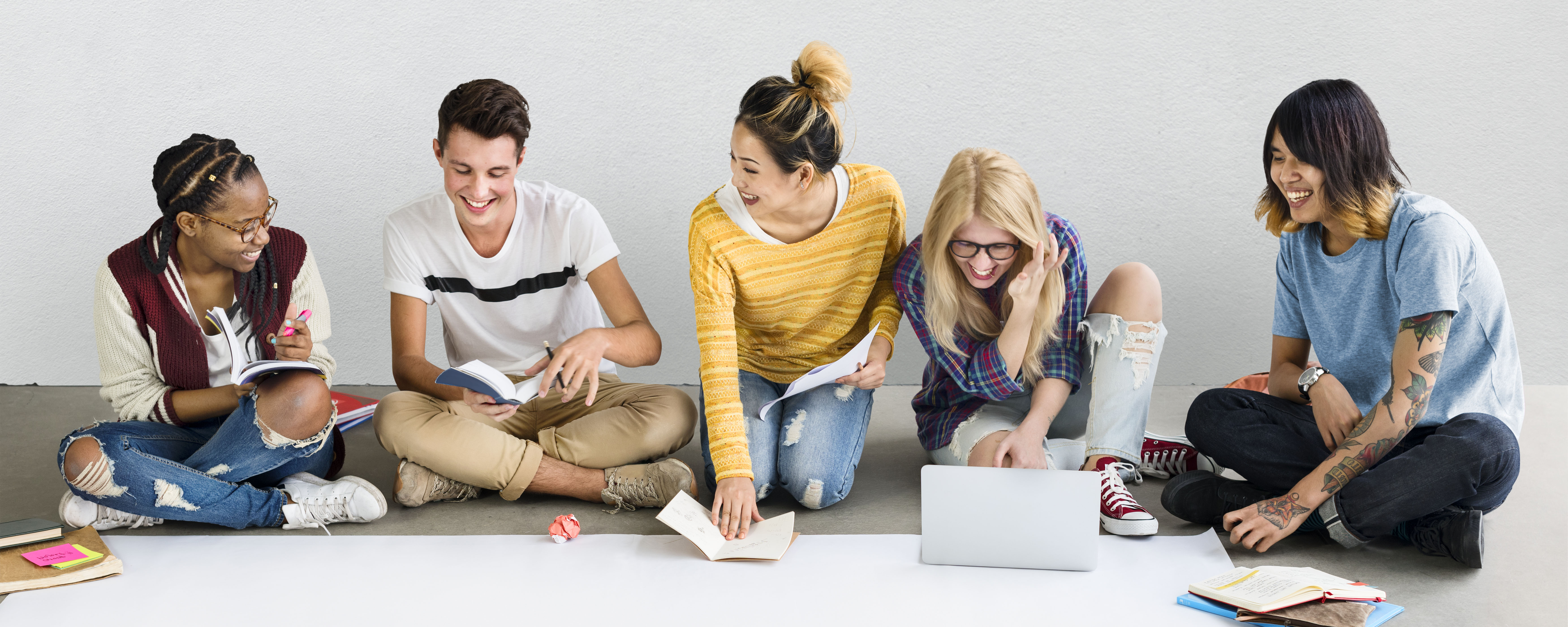 Diverse group of teens reading and using computers.