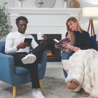 Diverse couple reading in front of a fireplace.