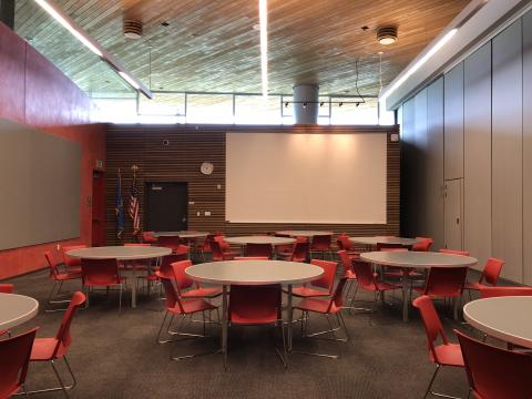 Meeting Room A at Northwest Library with round tables and a large white screen