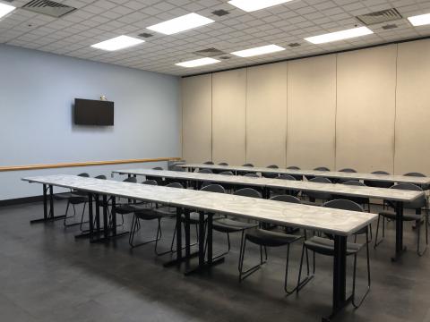 Interior image of Midwest City Meeting Room A with three rows of rectangular tables and chairs