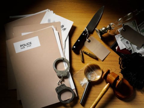 photo of a casefile, handcuffs, judge's gavel, and a knife marked as evidence