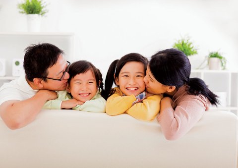 father and mother with two children on white sofa