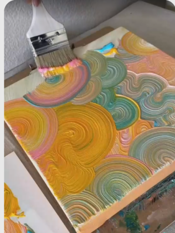 wide paint brush in the act of swirling globs of paint