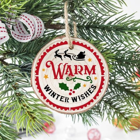 "warm winter wishes" along with silhouette of santa's sleigh and holly berries decorate this wood slice ornament