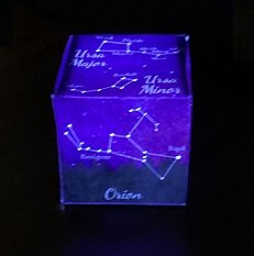 purple paper box in the dark illuminated from within through holes in the patterns of constellations