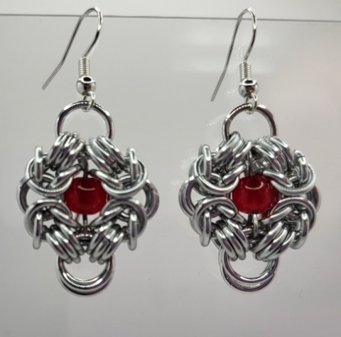 Earrings made with metal rings with a red bead in the center.