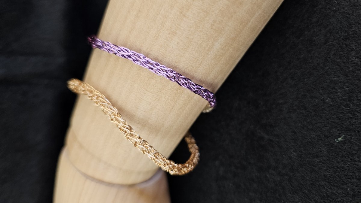 A mannequin wrist with two wire bracelets. 