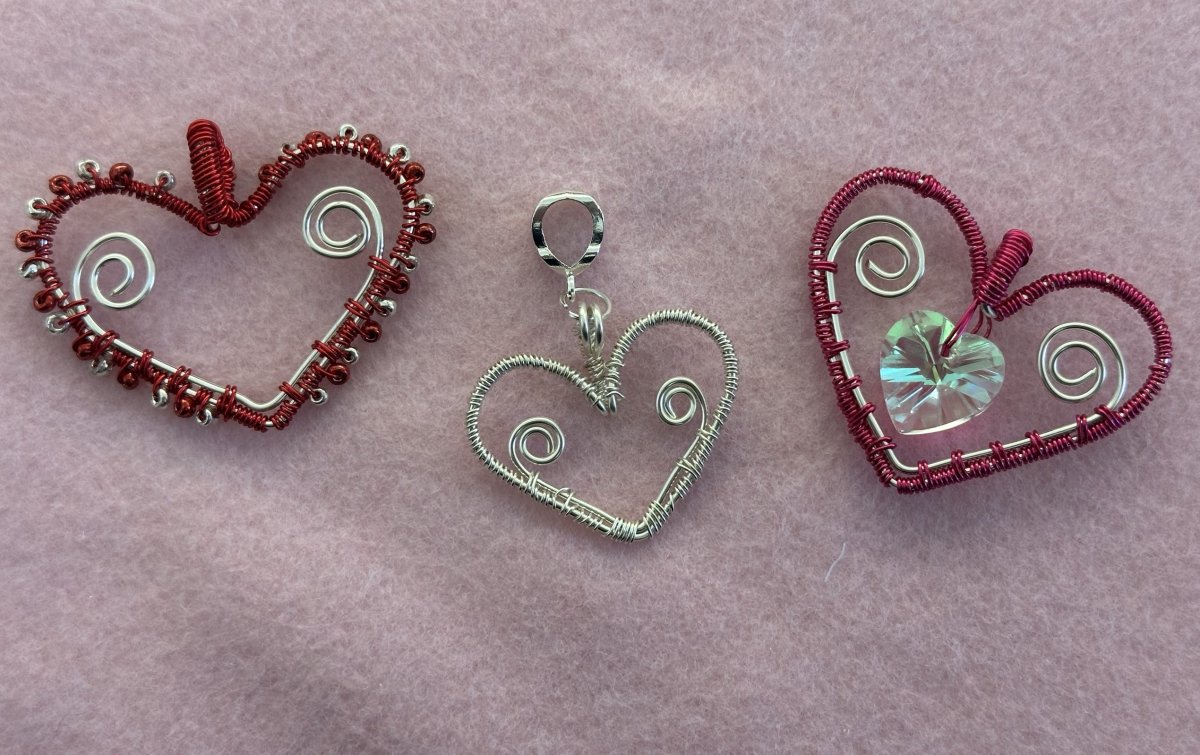 Three Wire Wrapped Heart Pendants on a pink background