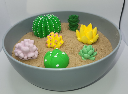 Painted plaster succulents arranged in a grey bowl.