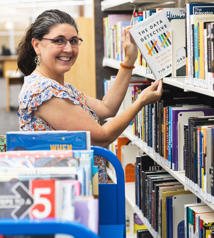 Librarian getting book off a shelf.