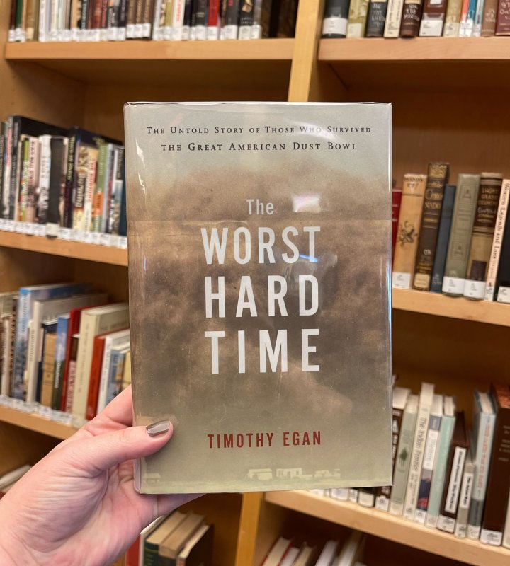 The Worst Hard Time book held in front of a bookshelf.